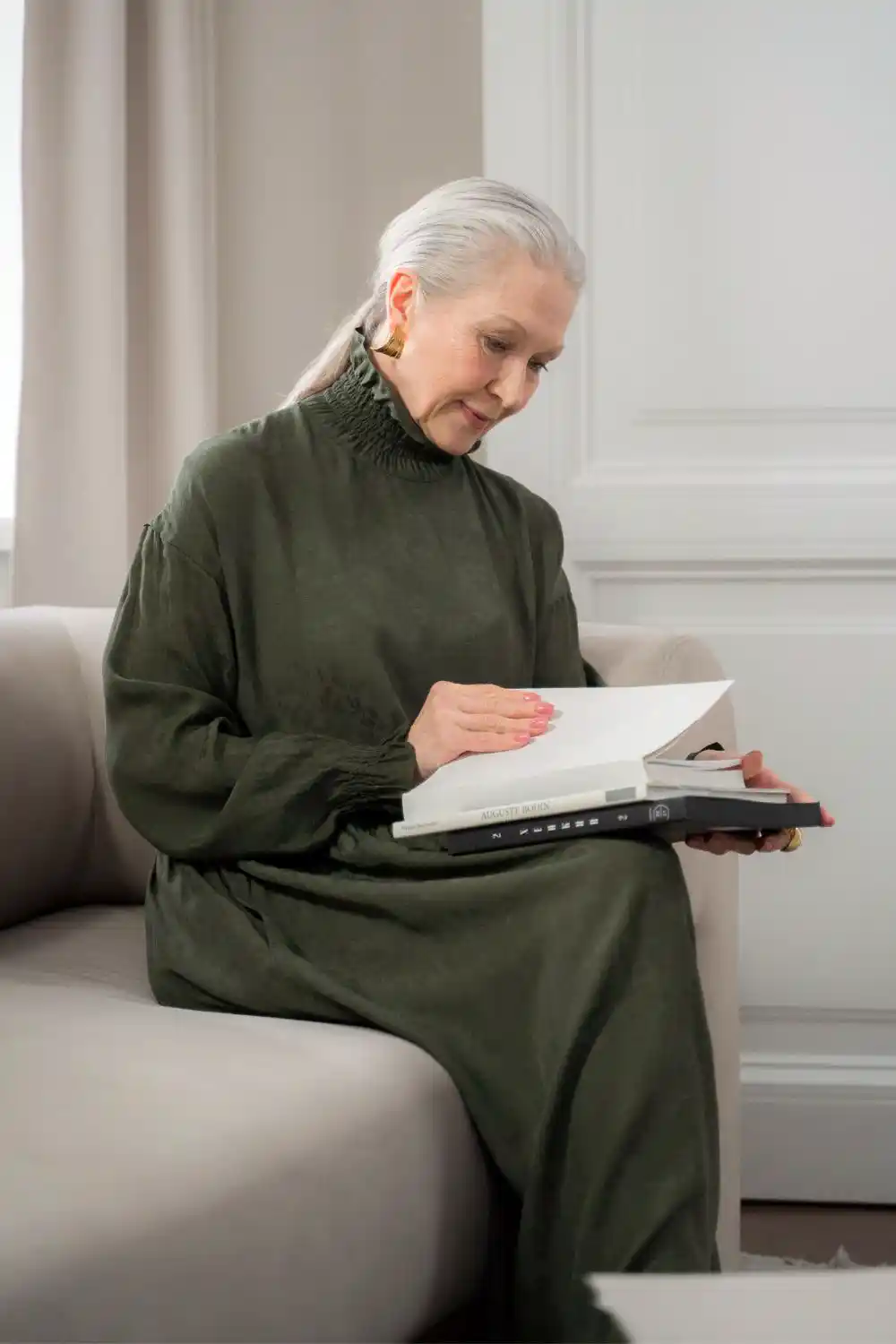 Woman in Olive Dress Sitting on Sofa Reading Book