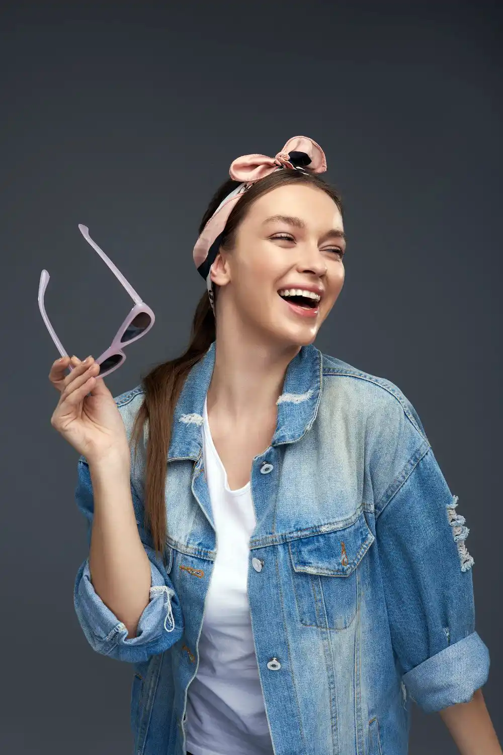 Young lady in bow headband holding sunglasses