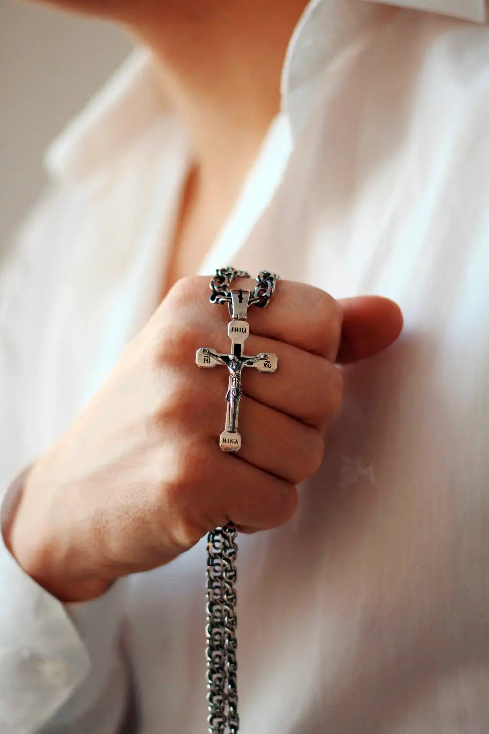 Person Holding a Silver Cross Necklace