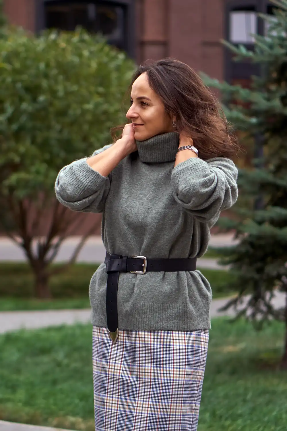 Woman dressed green voluminous sweater and black belt, skirt